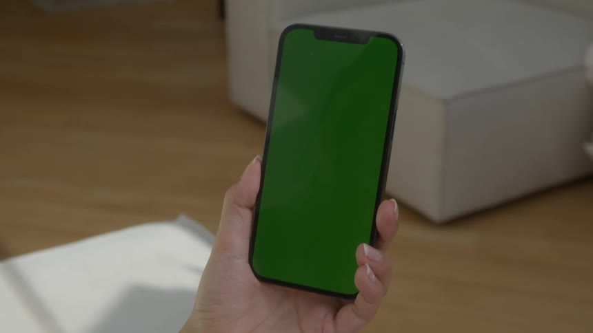 A woman holds and looks at a smartphone