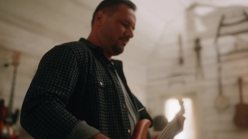 Man in a studio playing guitar and next to him a colleague playing drums