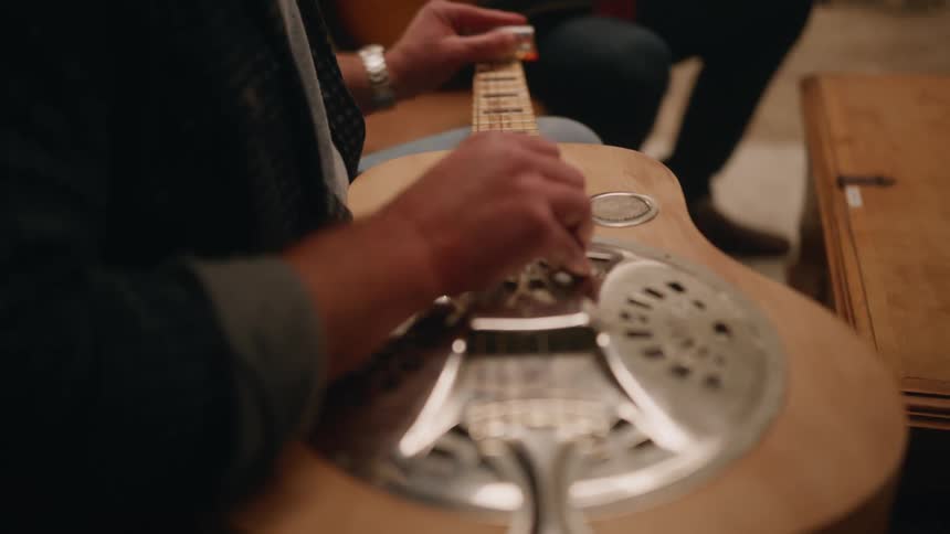 Closeup of a mans hands adjusting the strings of a guitar