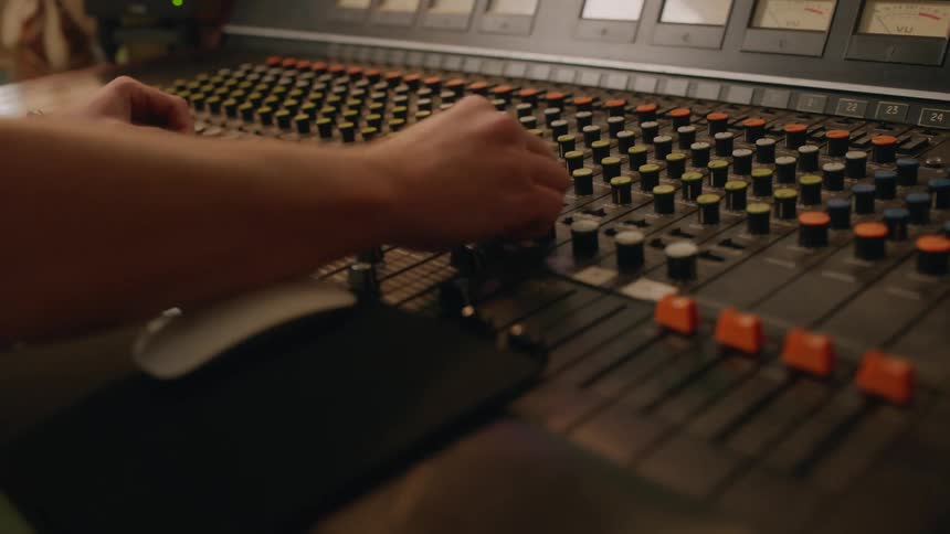 A male audio engineer operating a mixing console