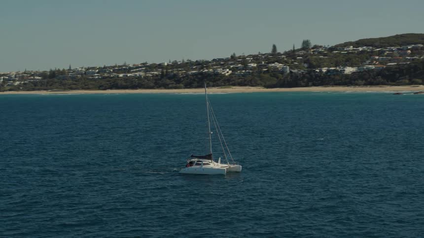 Yacht in the middle of the sea with the coast and a city in the background