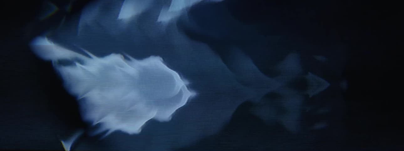 A closeup of a blue screen with distorted shapes flashing and fading