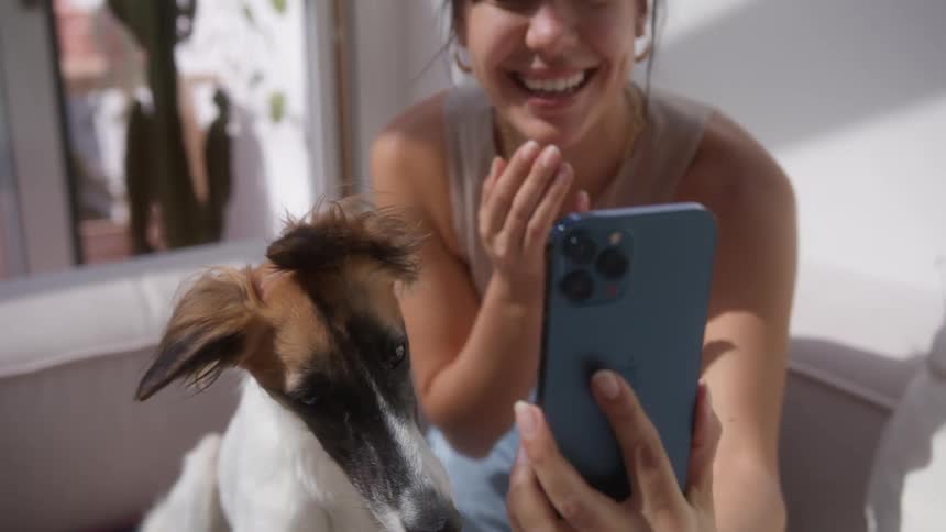 A woman laughs as she takes a selfie with her dog