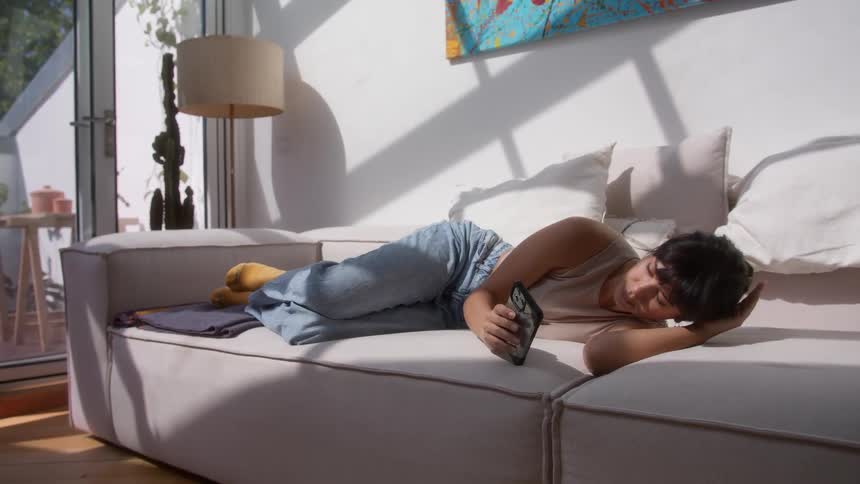 Woman lying on the couch using her cell phone