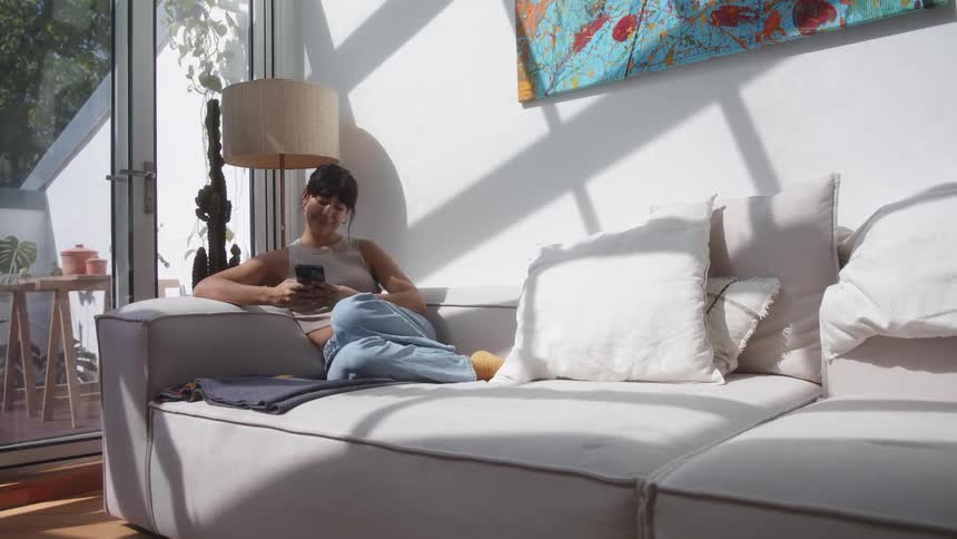 Woman sitting on the couch using her cell phone