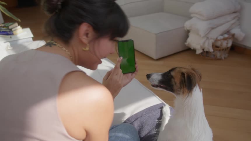 Woman taking selfie with iphone with her dog by her side