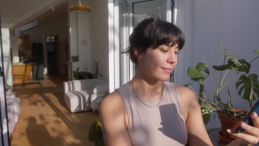 A woman walks on her porch talking on a cell phone