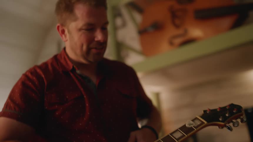 A clip of a man holding a guitar