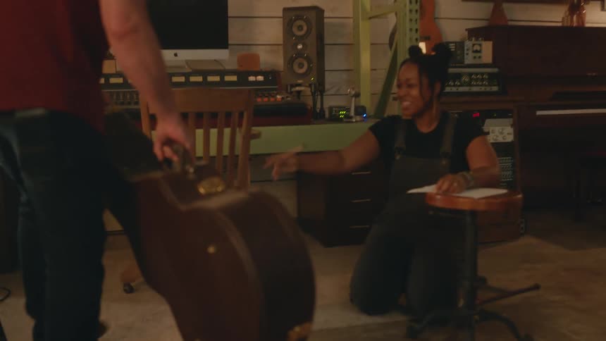 Man walks in to a studio carrying his guitar case