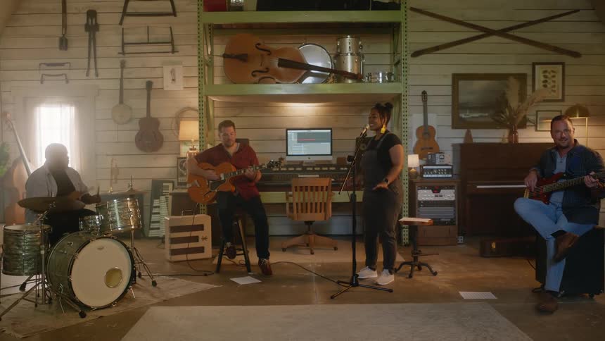 Four band members play instruments in a music room