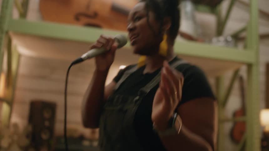 Band rehearsing in a studio with a vocalist, drummer, bassist, and a guitarist