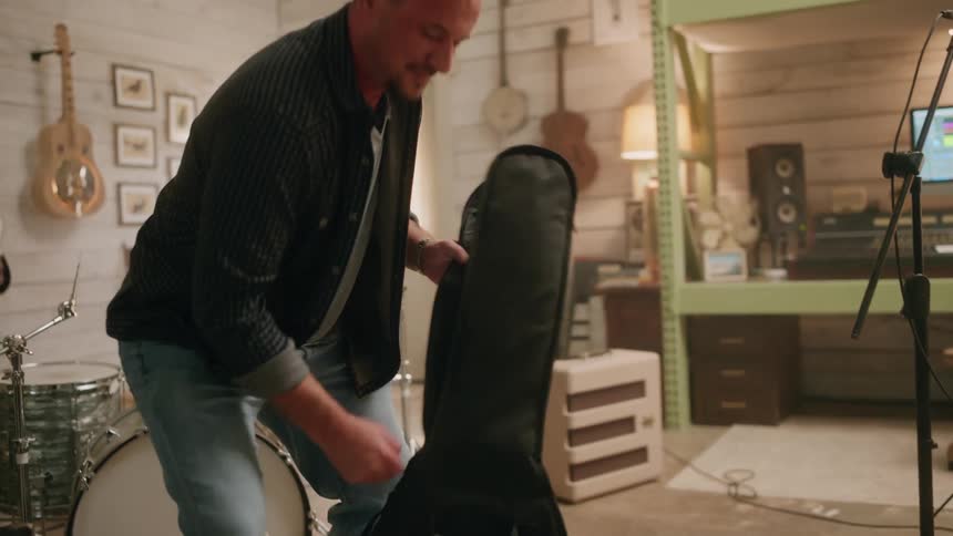 A man is packing up his guitar in a bag