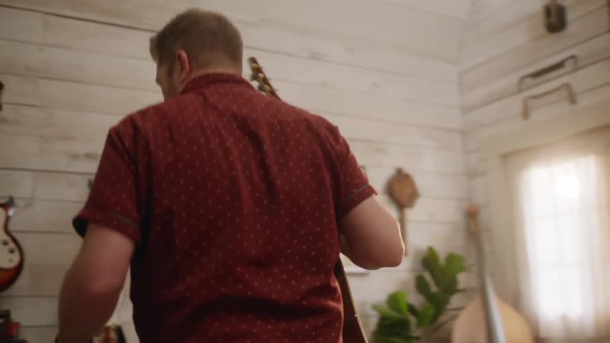 A musician unplugs and hangs up his guitar after playing it