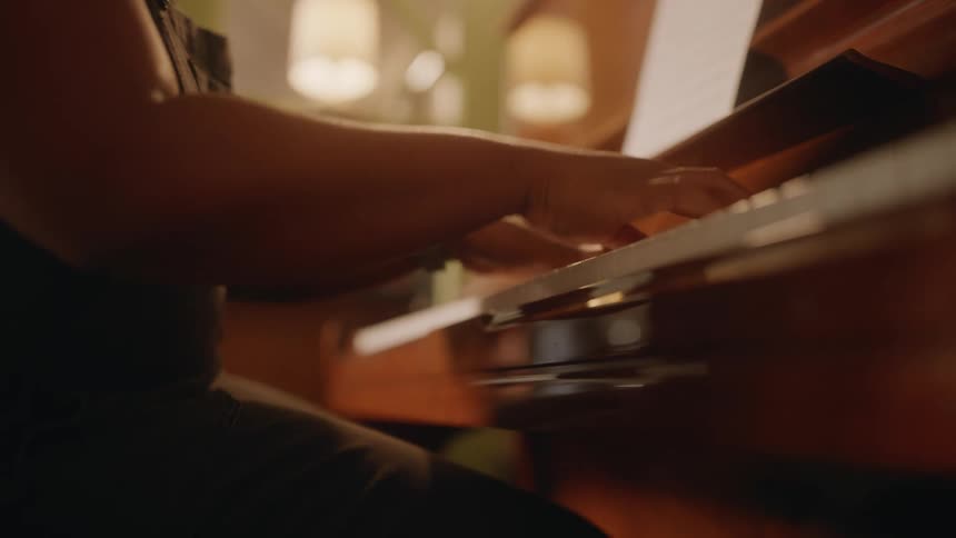 Woman wearing a jumpsuit plays the piano