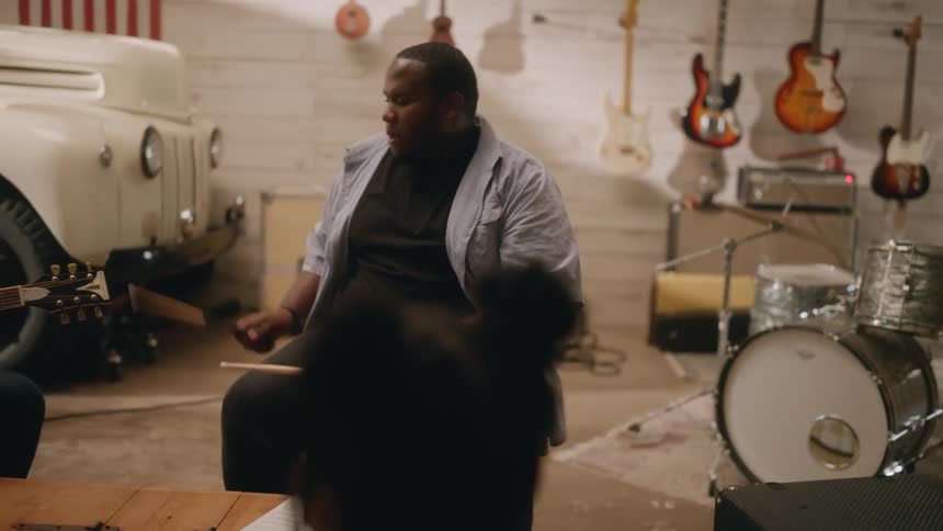 A man is playing drums on his knees in the studio