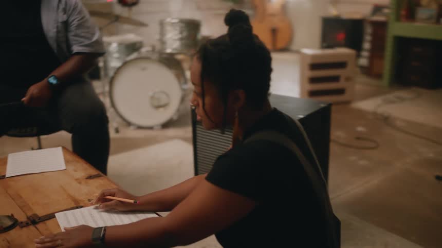 A woman at a table with a group of musicians composing a song