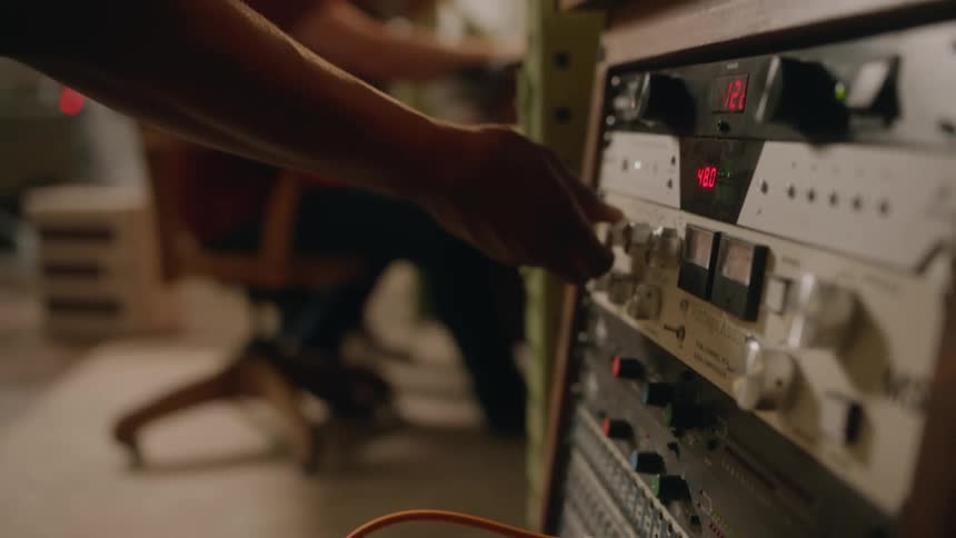 Man plugs in cable and adjusts settings in recording studio