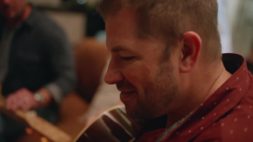Musicians play guitars while sitting in living room
