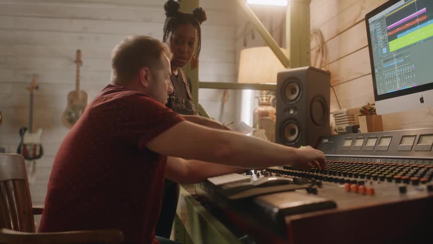 Man and woman in a studio checking a music mixer