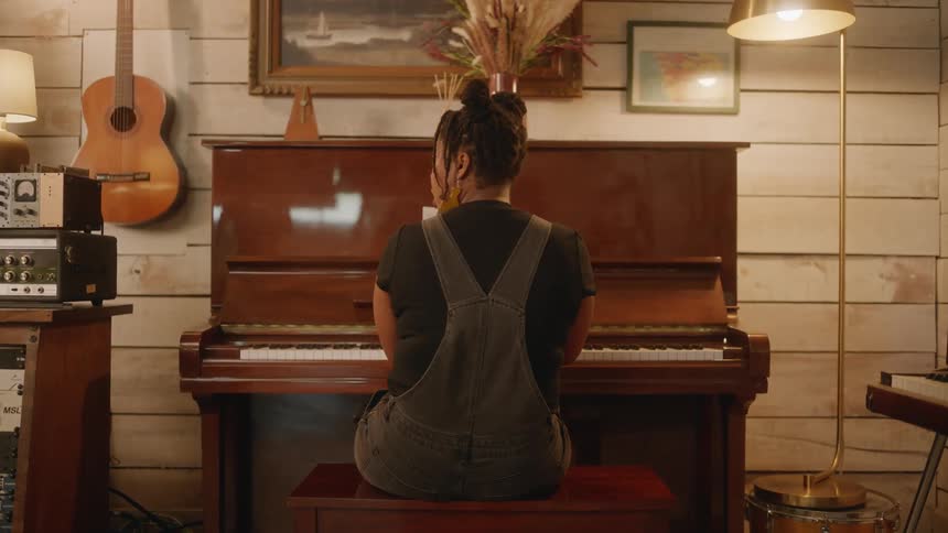 A woman with dreadlocks wearing a jumpsuit while playing the piano