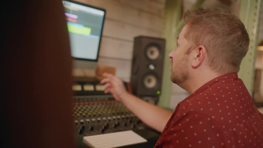 Two musicains collaborating and having a discussion in a professional recording studio