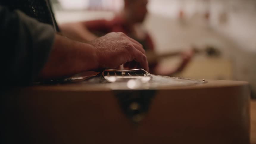 Two men sitting and playing guitars together