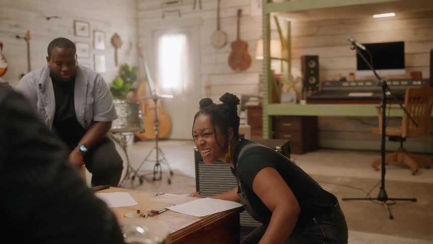 Fourperson band singing and cheering in a music studio