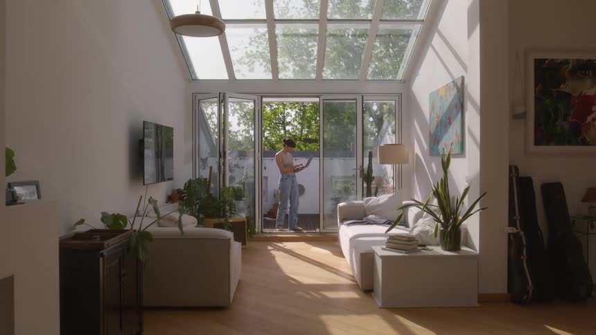 Woman in the backyard of a house next to the living room using a laptop