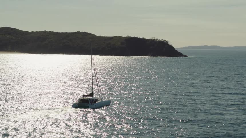 A white sailboat with its sails down floats on calm water