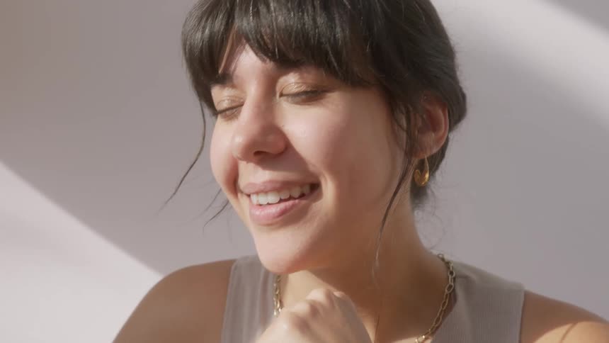 A woman with a happy playful expression holding their fists up near their face in a playful or excited gesture