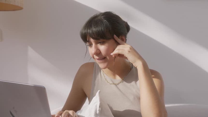 A woman smiles as she uses her laptop