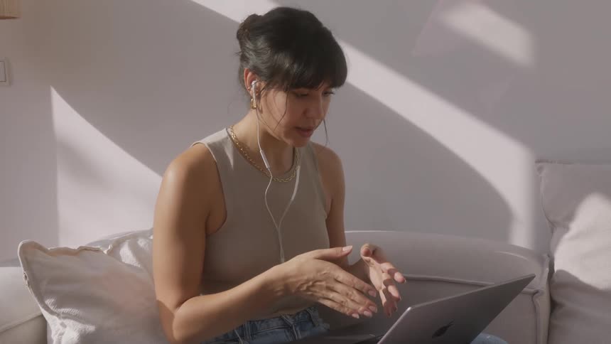 Woman sitting with headphones talking happily with her laptop on her lap
