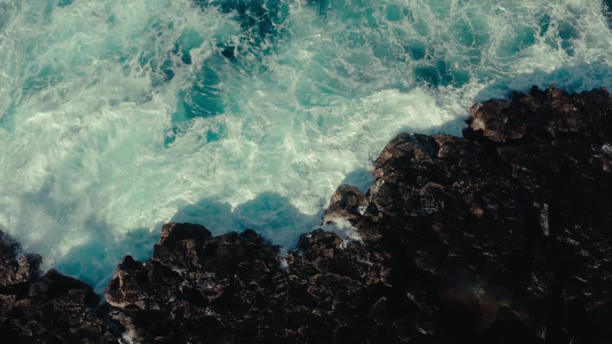 Top view of ocean waters hitting rock at seaside