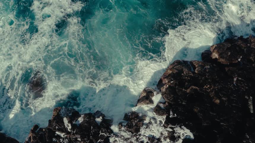Waves foam as they hit a rocky coast