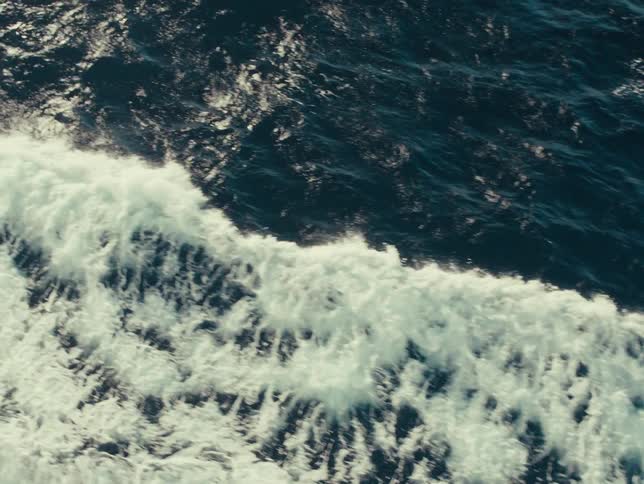 Ocean waves seen from above move across the waters surface