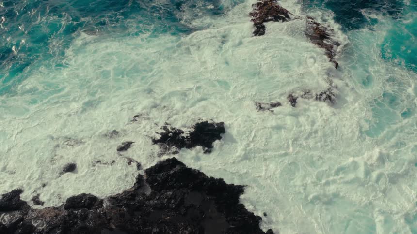 Powerfully churned waves crash against the rocky coastline sending plumes of foamy spray high into the air