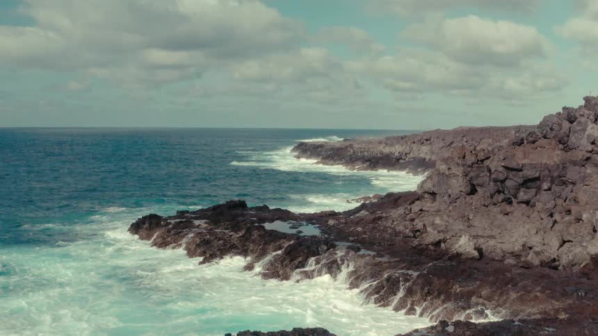 Blue ocean with foamy waves crashing on the rocky shore