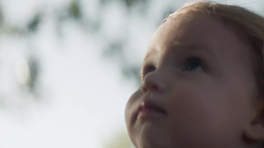 Young child pointing towards the sky and then looking down and forward
