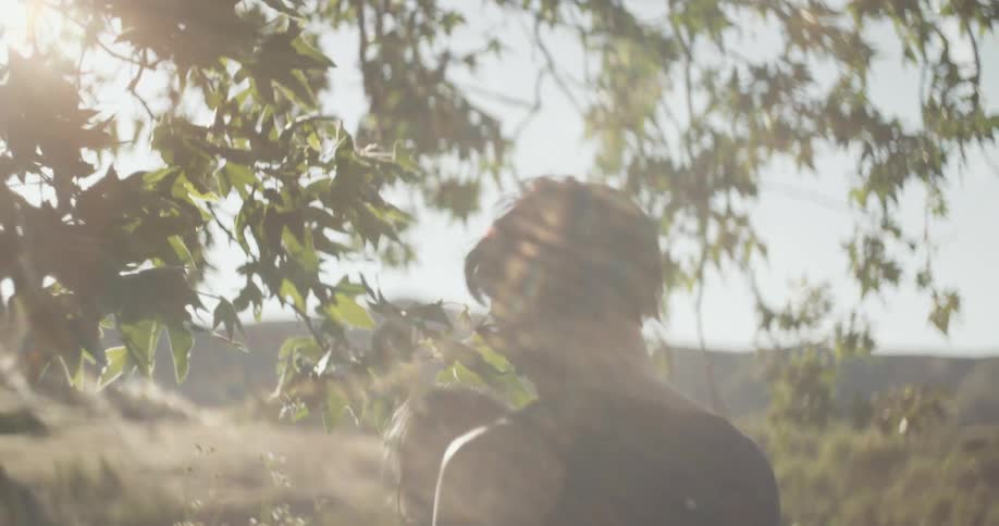 A woman holds a baby up through the leaves in the sunlight