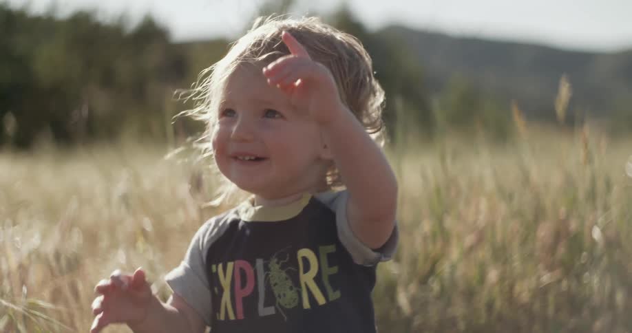 A young boy smiling outdoors in a field