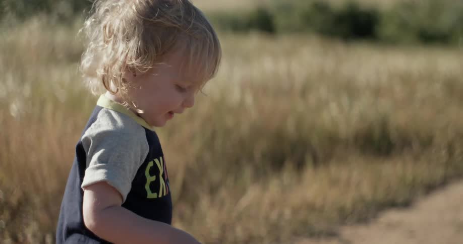 A child is walking down a dirt trail