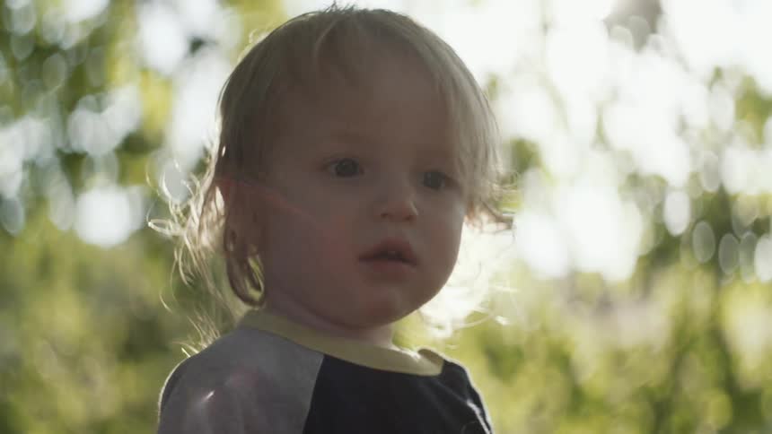 Toddler standing outdoors with the sun shining brightly behind them