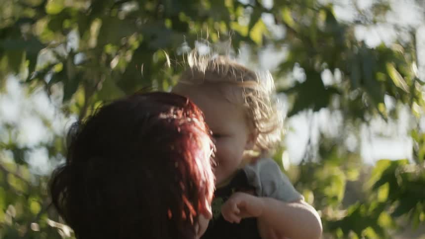 A woman playfully lifts a young child