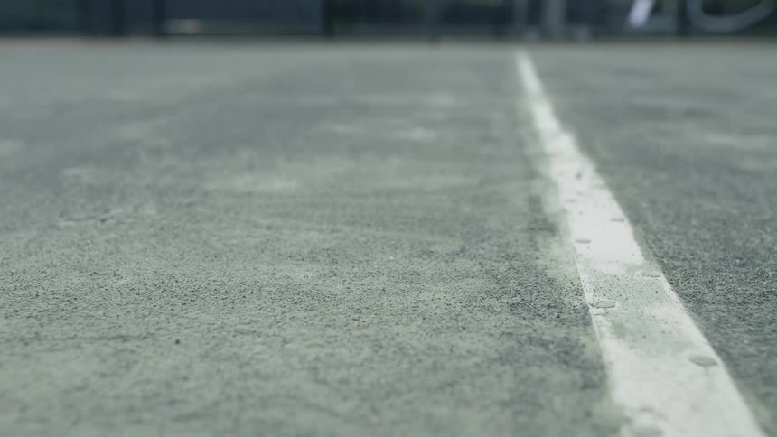 Green tennis ball bouncing onto a court