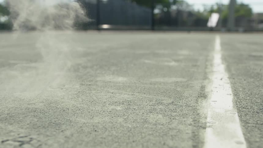 Green tennis ball bouncing on an open air court