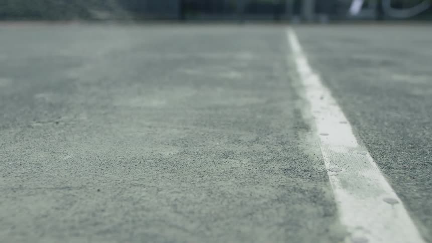 Green tennis ball bouncing on a court and releasing dust