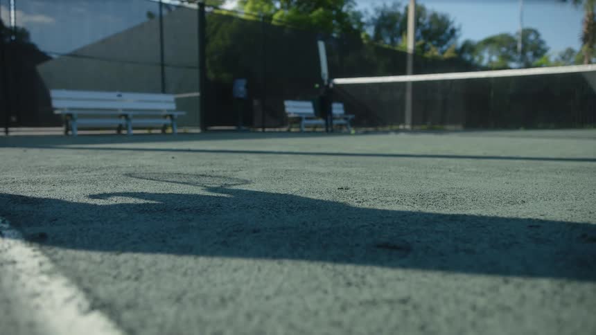 A shadow of a tennis player returning a shot on a court
