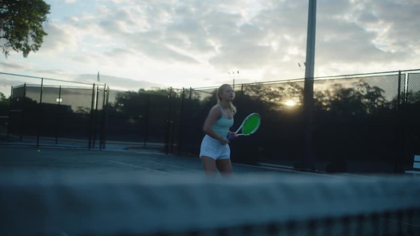 Blonde woman playing tennis on an open air court
