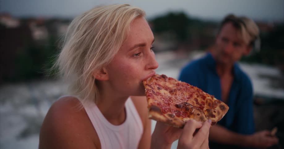 A woman eats a slice of people while sitting next to a man