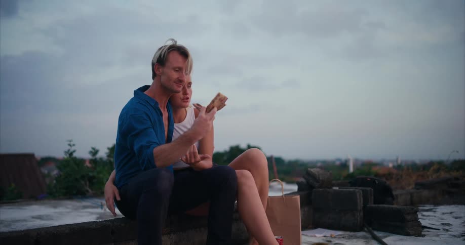 A man and woman hug and kiss while eating